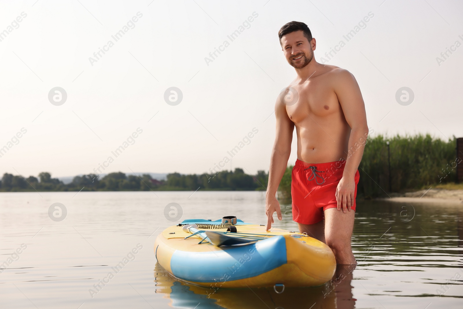 Photo of Man standing near SUP board in water, space for text