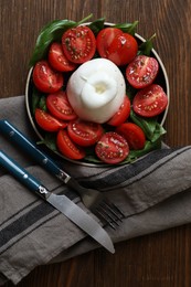 Delicious burrata cheese with tomatoes and basil served on wooden table, flat lay