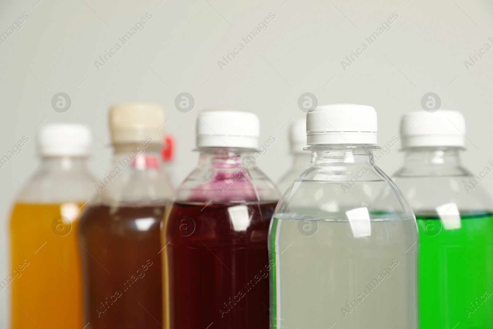 Photo of Bottles of soft drinks on grey background, closeup