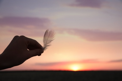 Photo of Woman with feather outdoors on sunset, closeup. Healing concept