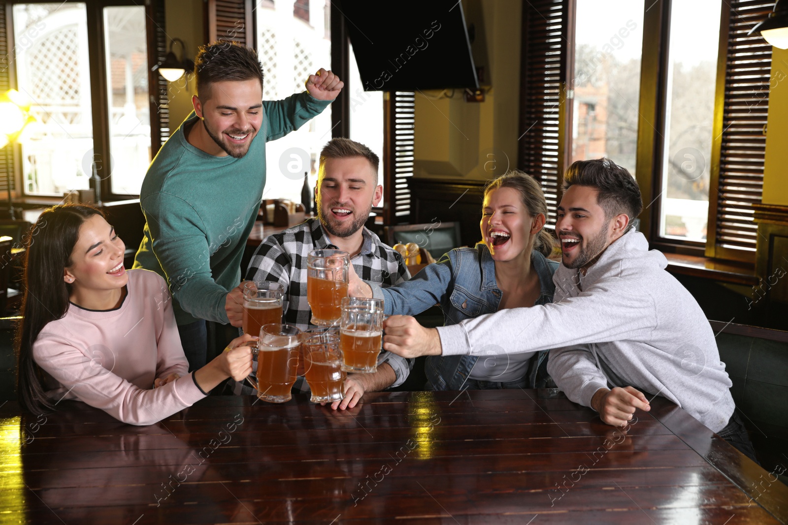 Photo of Group of friends celebrating victory of favorite football team in sport bar