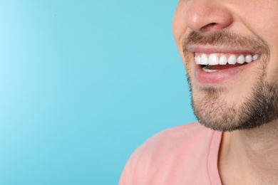 Photo of Smiling man with perfect teeth on color background, closeup. Space for text