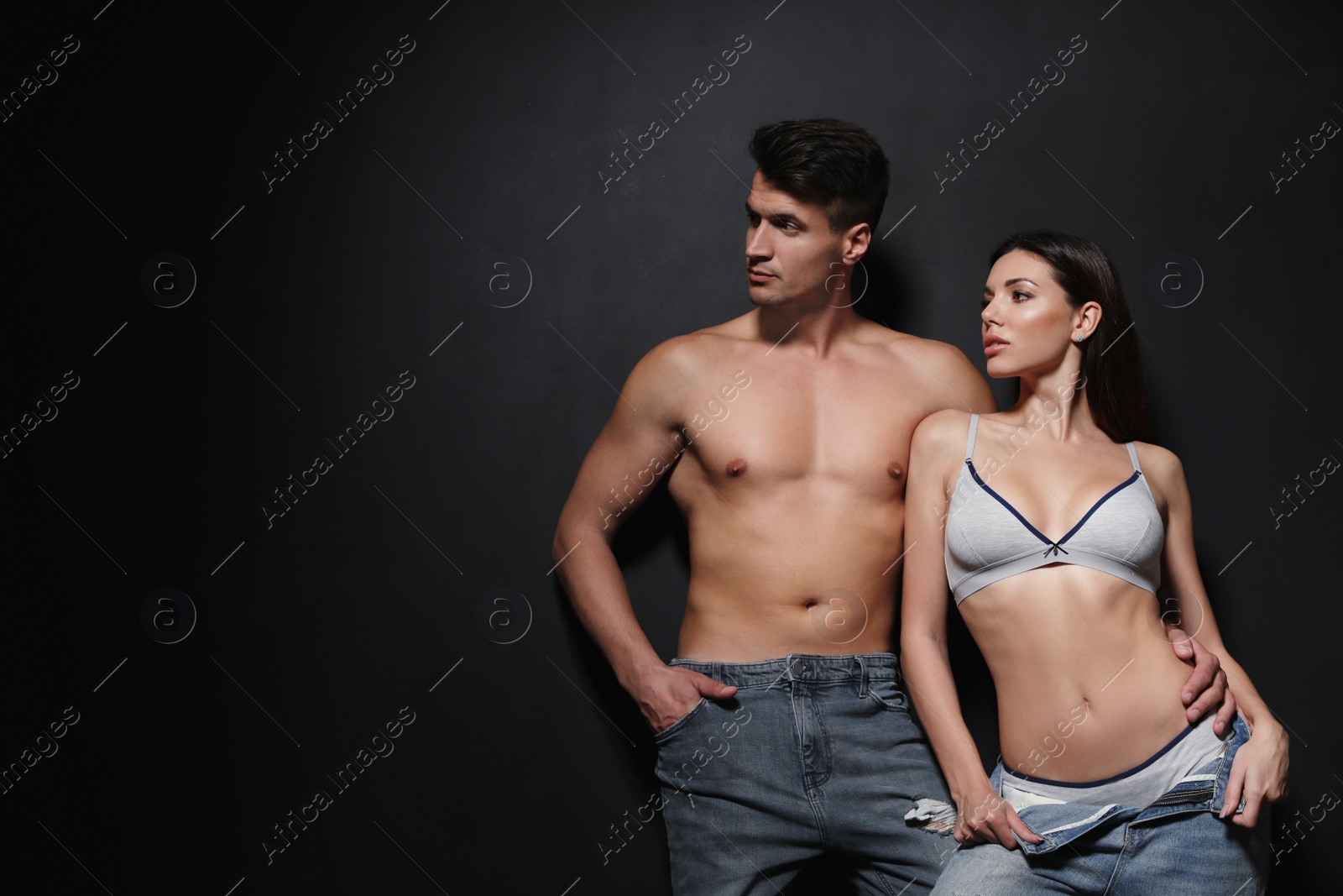 Photo of Young couple wearing underwear and jeans on black background, space for text