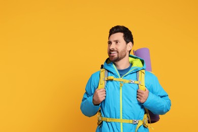 Photo of Happy man with backpack on orange background, space for text. Active tourism