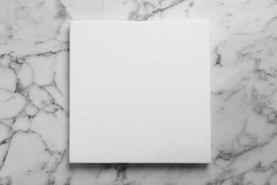 Photo of Blank canvas on white marble background, space for text