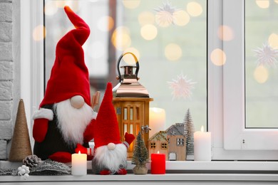 Photo of Cute Christmas gnomes and other festive decorations on windowsill in room, space for text