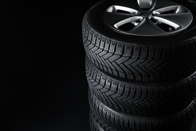 Photo of Set of wheels with winter tires on black background, closeup. Space for text