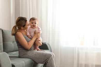 Photo of Young woman with her cute baby at home. Space for text