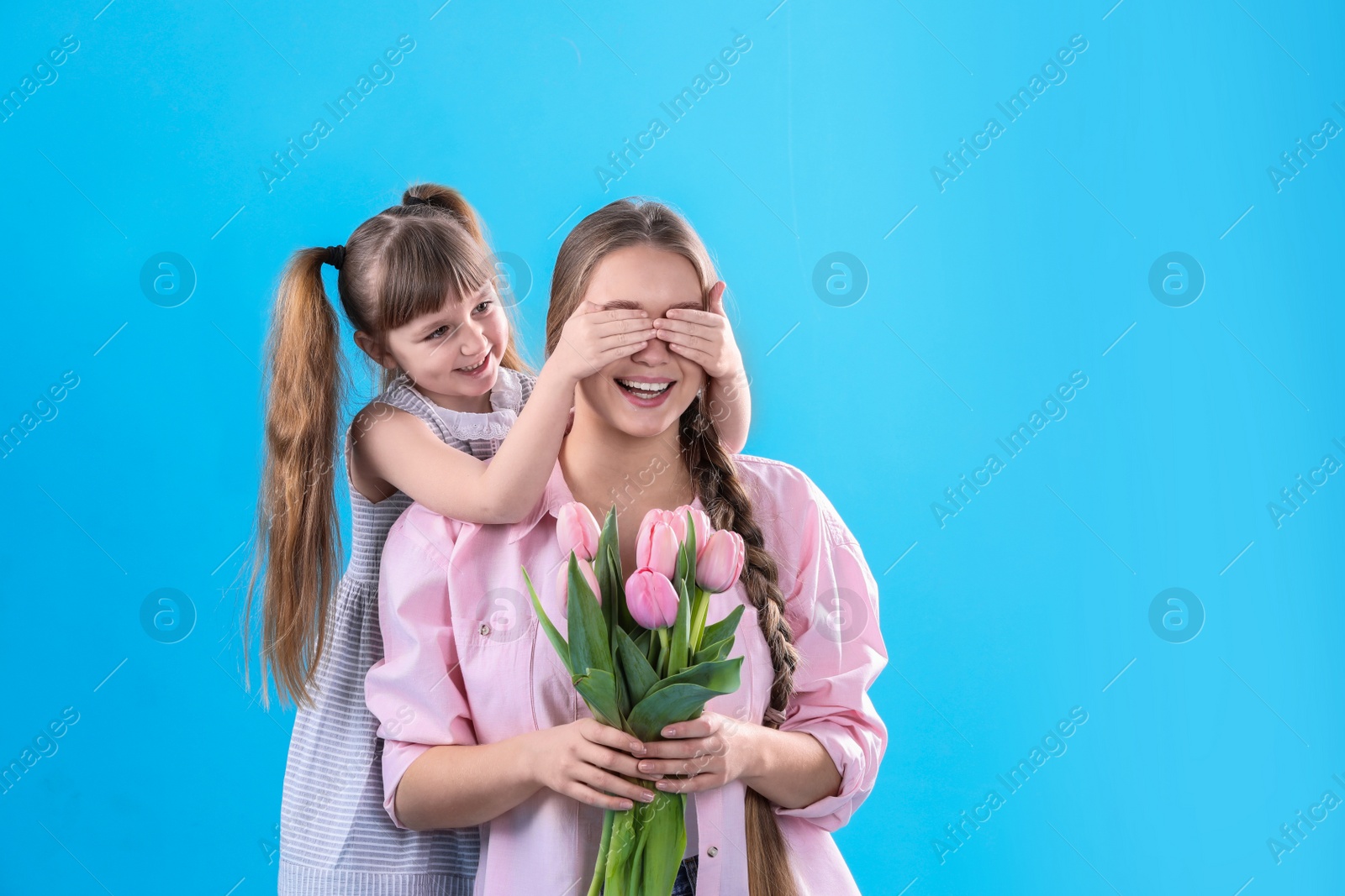 Photo of Happy mother and daughter with flower bouquet on color background. International Women's Day