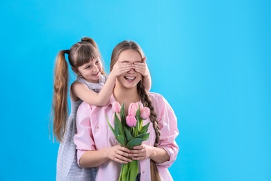 Happy mother and daughter with flower bouquet on color background. International Women's Day