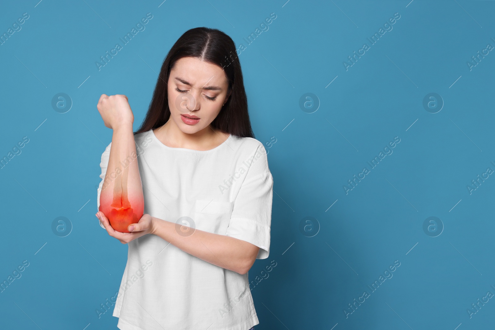 Image of Arthritis symptoms. Young woman suffering from pain in elbow on light blue background, space for text