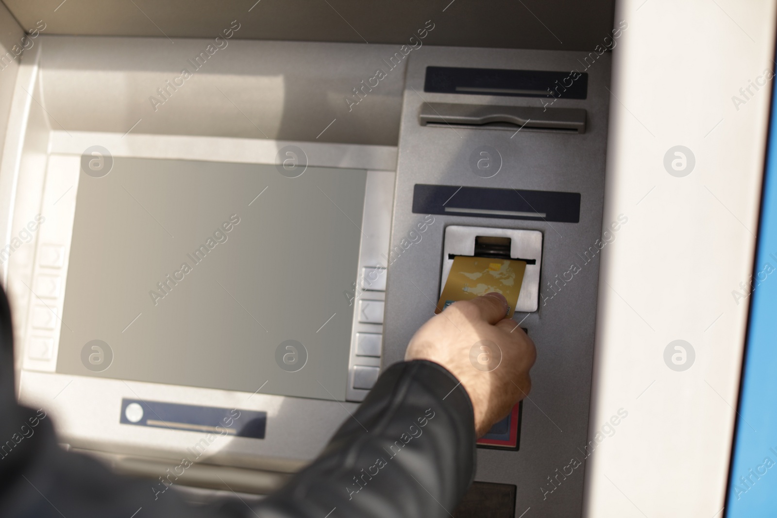 Photo of Man inserting credit card into cash machine outdoors, closeup