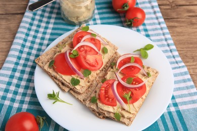 Photo of Fresh crunchy crispbreads with pate, tomatoes, red onion and greens on table