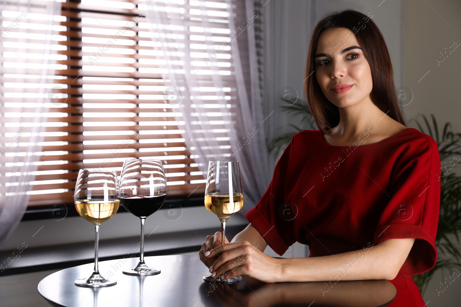 Photo of Beautiful young woman tasting luxury wine at table. Space for text