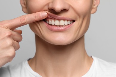 Photo of Woman showing healthy gums on light background, closeup
