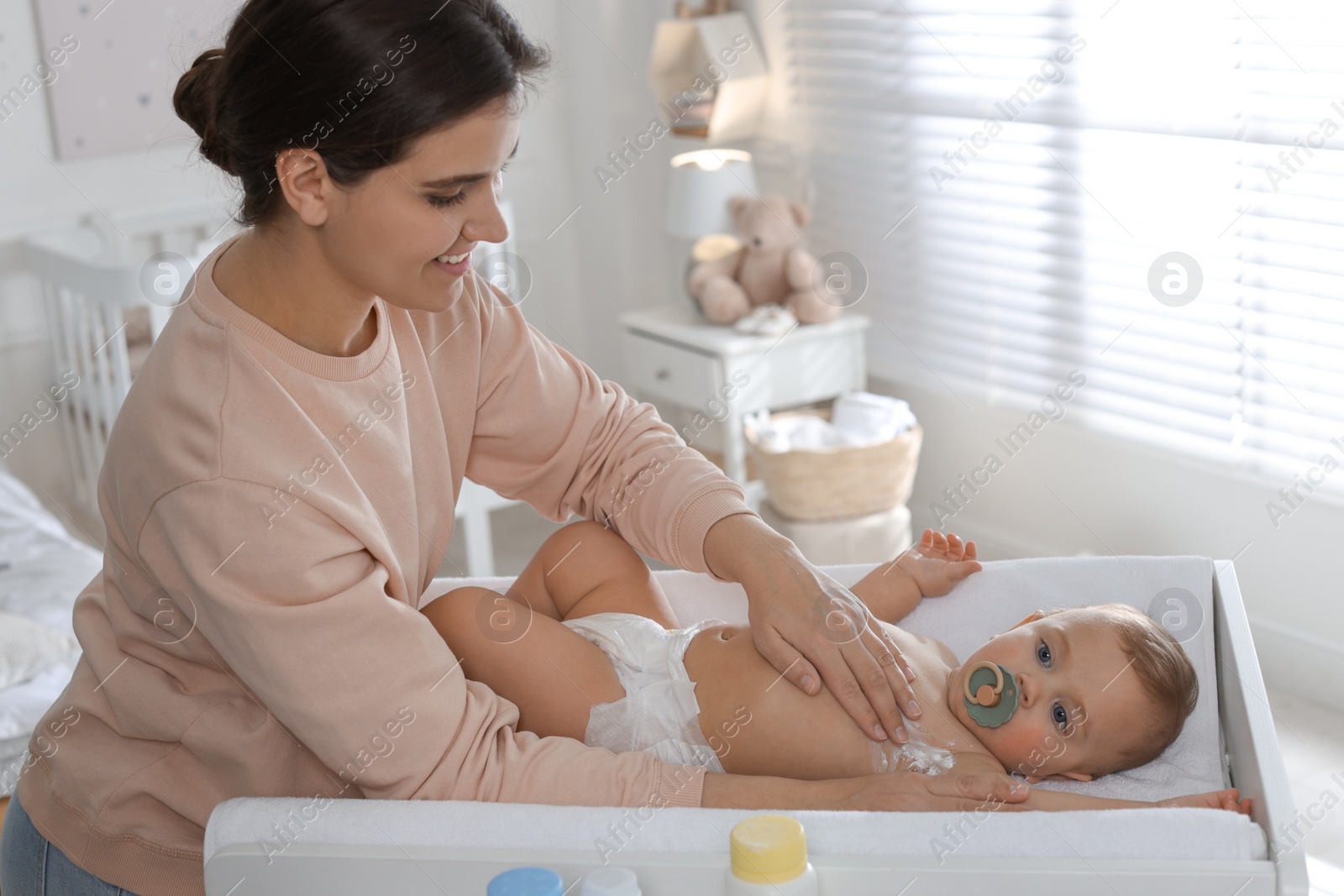 Photo of Mother applying dusting powder on her cute baby at home