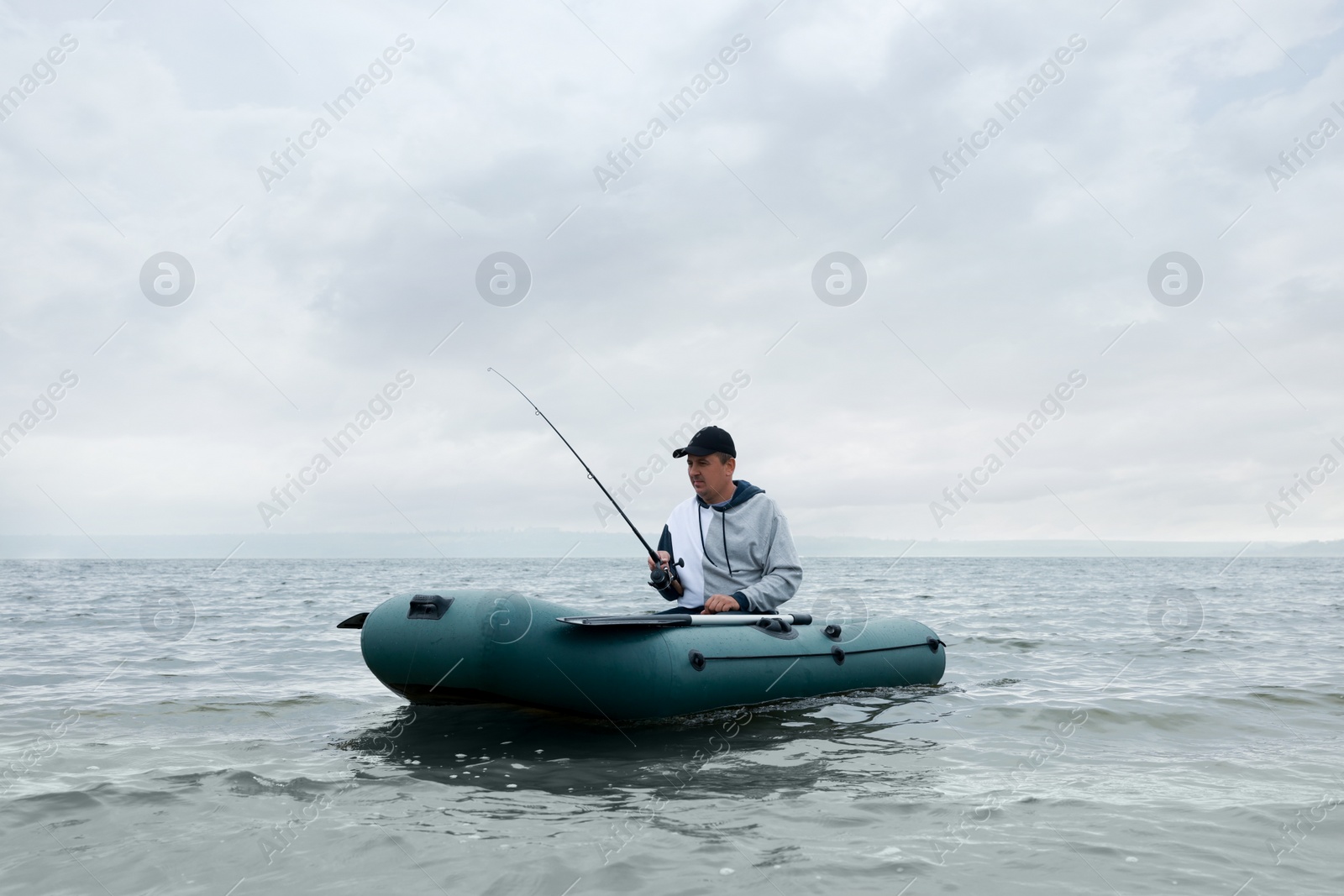 Photo of Man fishing with rod from inflatable rubber boat on river