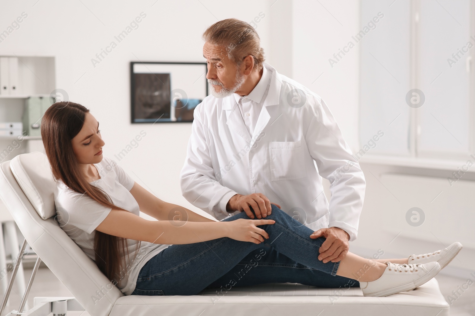 Photo of Orthopedist examining patient with injured knee in clinic