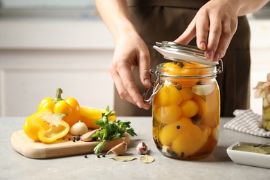 Photo of Woman with jar of pickled peppers at table, closeup