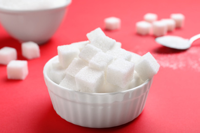 Photo of Refined sugar cubes in bowl on red background
