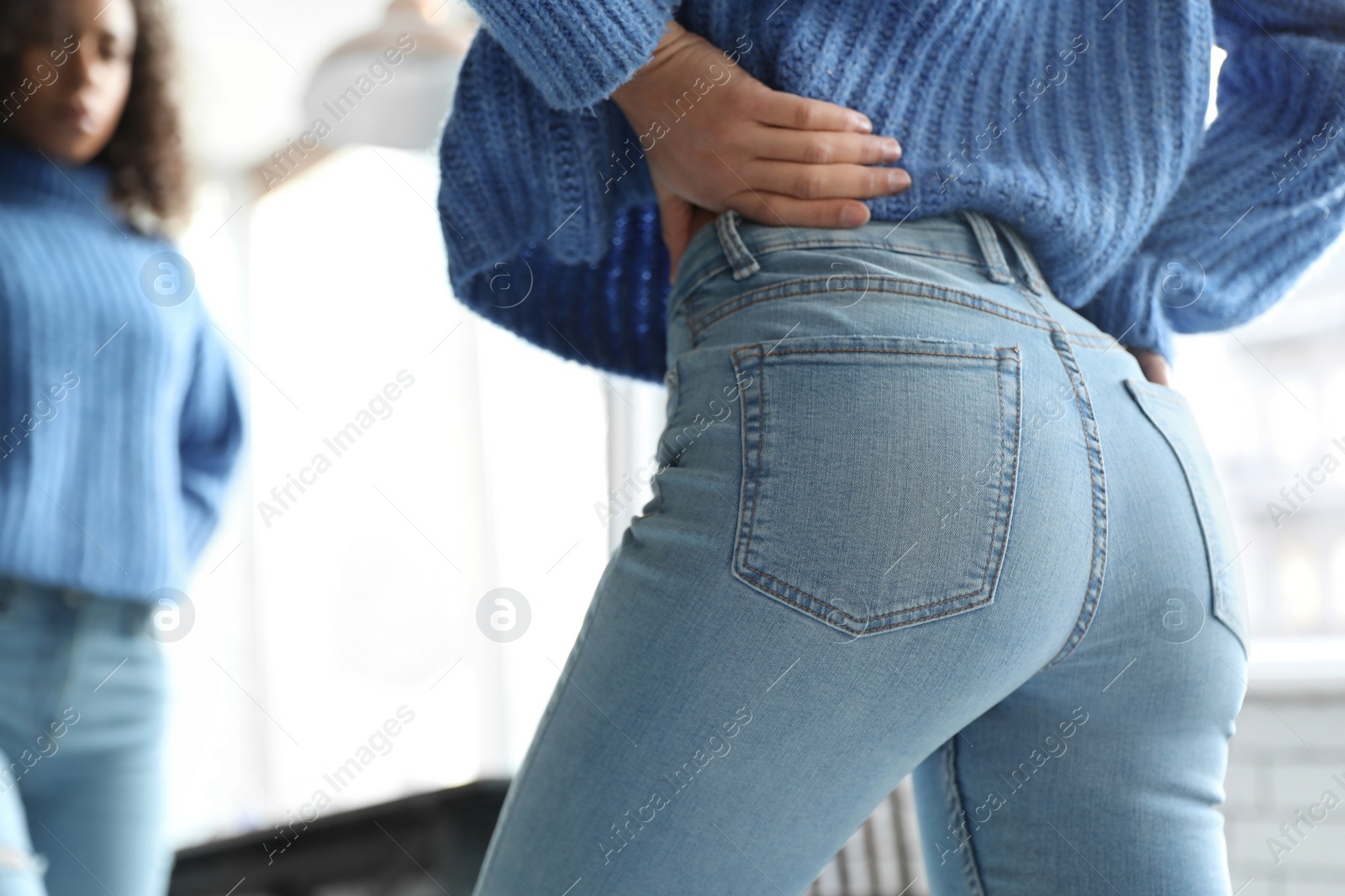 Photo of Woman wearing jeans near mirror indoors, closeup