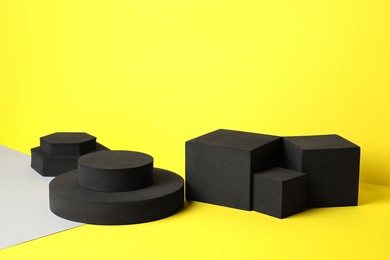 Photo of Many black geometric figures on yellow background. Stylish presentation for product