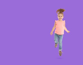 Cute girl jumping on violet background, space for text