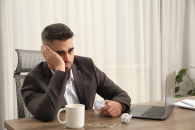 Photo of Sad businessman sitting at table in office