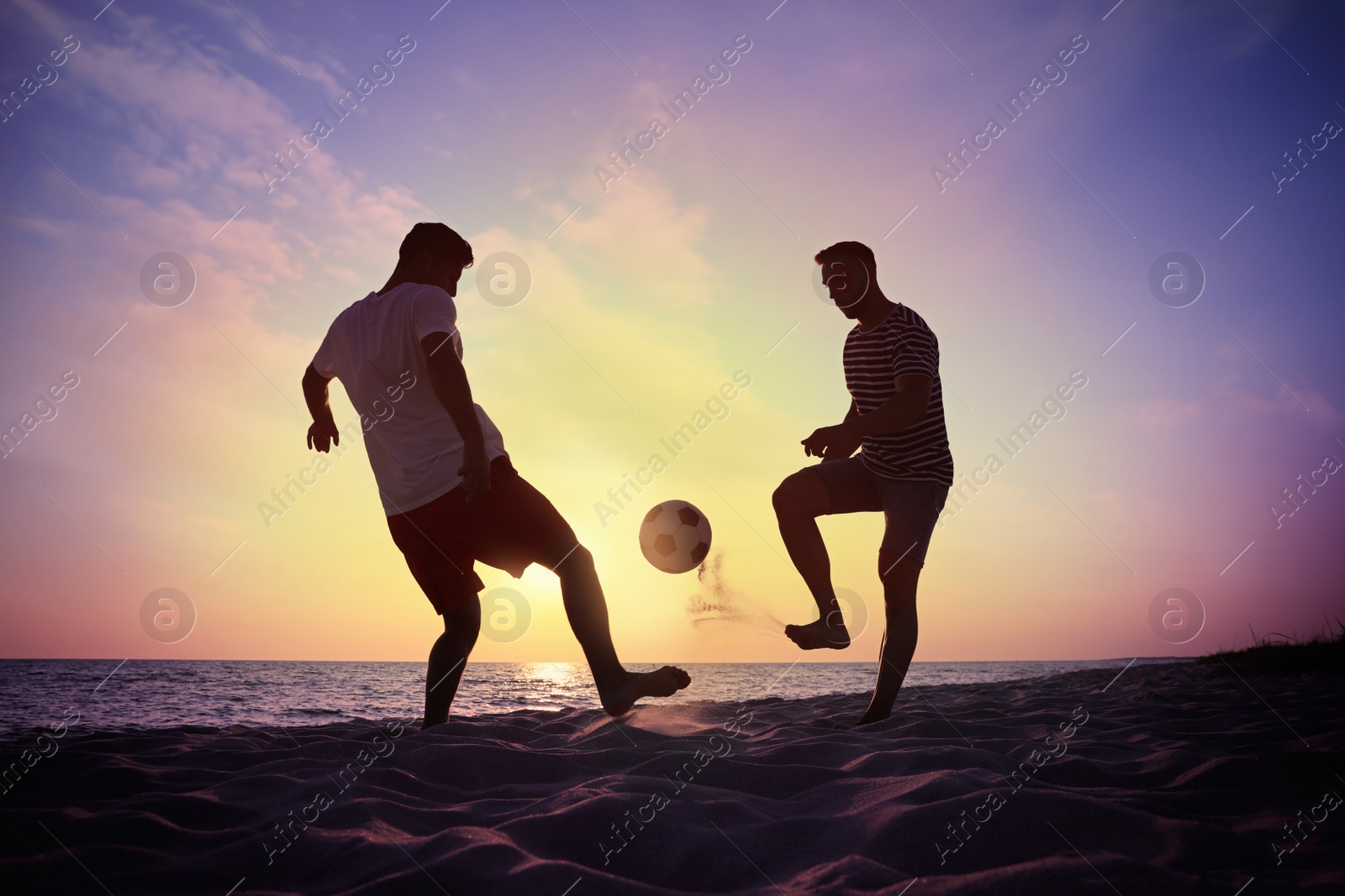 Photo of Friends playing football on beach at sunset