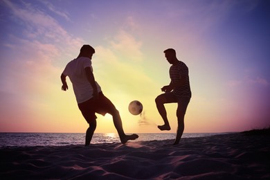 Friends playing football on beach at sunset