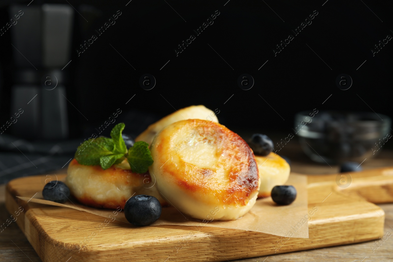 Photo of Delicious cottage cheese pancakes with blueberries and mint on wooden table