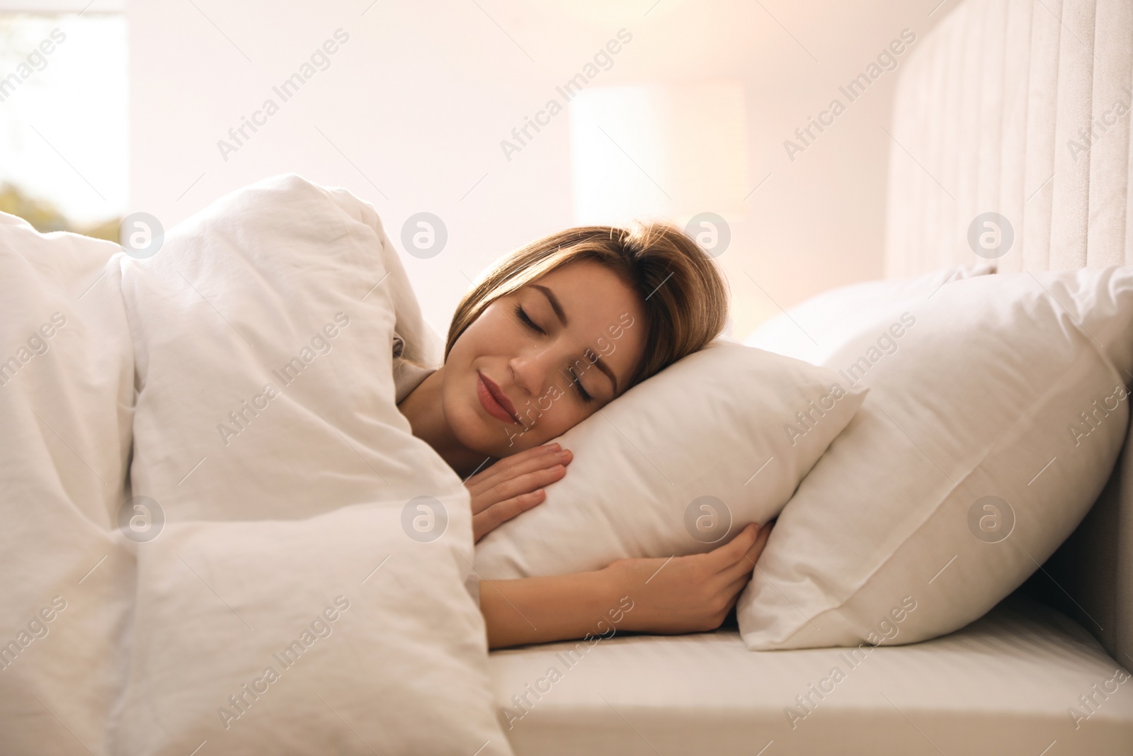 Photo of Woman under warm white blanket sleeping in bed indoors