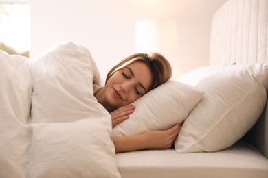 Woman under warm white blanket sleeping in bed indoors