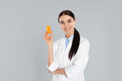 Professional pharmacist with pills on light grey background