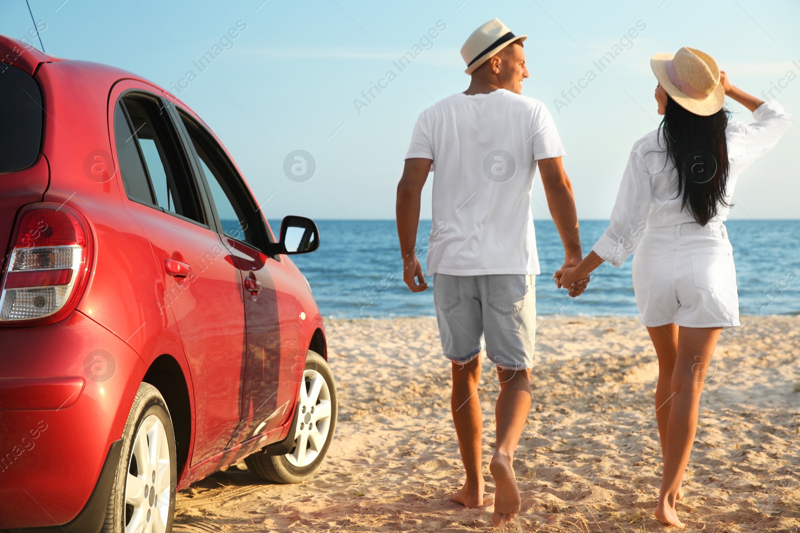 Photo of Happy couple walking on sandy beach, back view. Summer trip