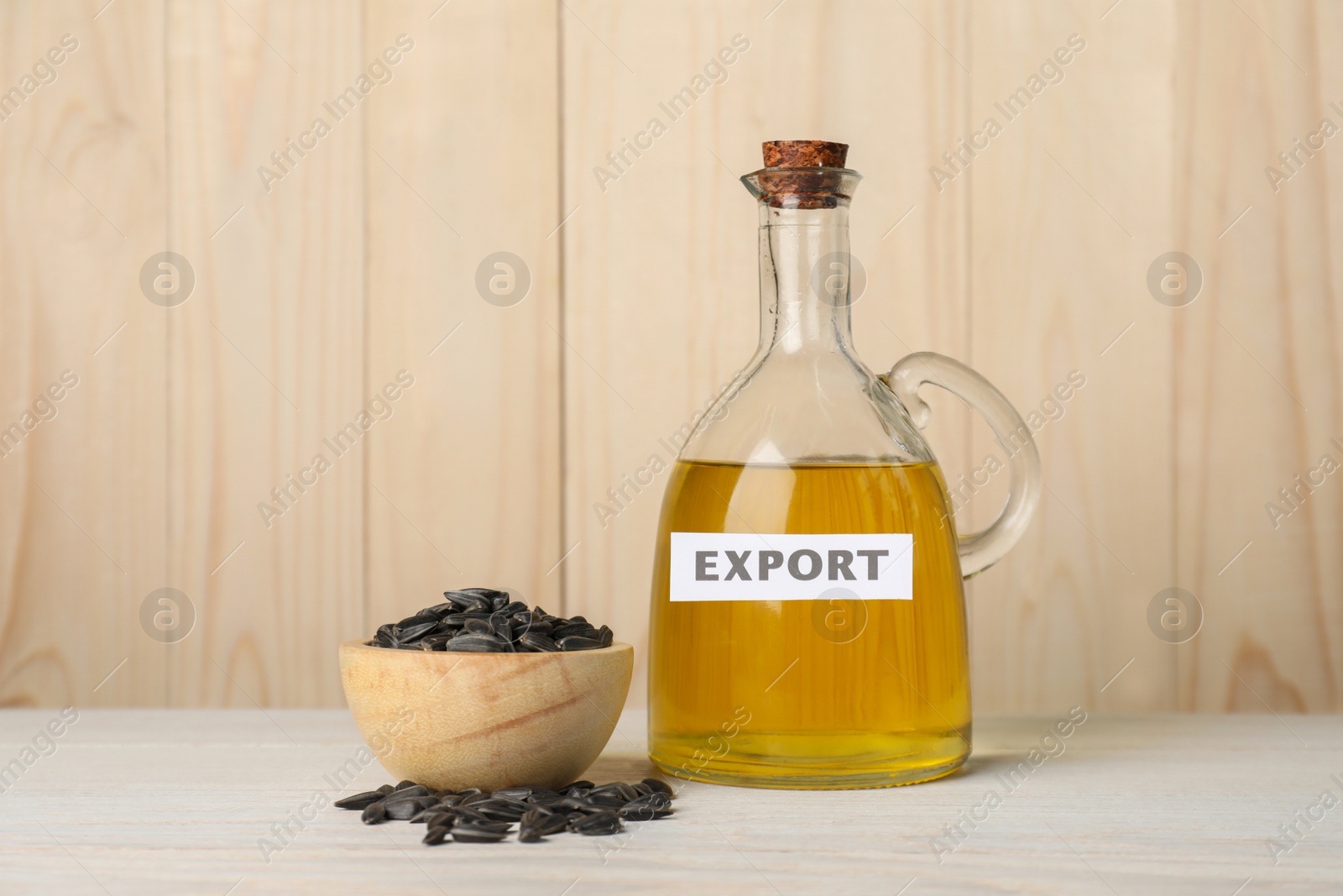 Photo of Sunflower oil and bowl with seeds on white wooden table, space for text. Export concept