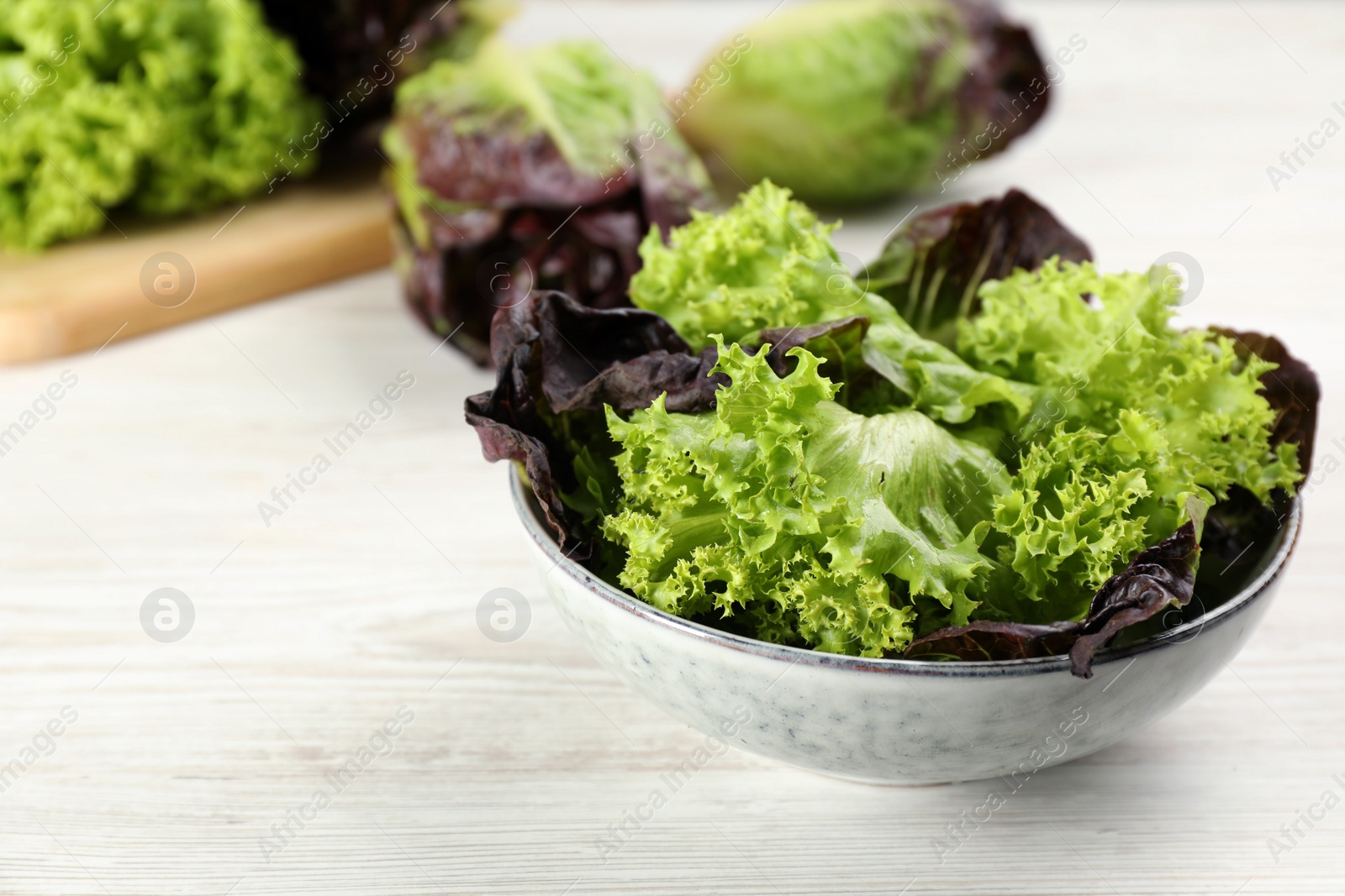 Photo of Different sorts of lettuce on white wooden table