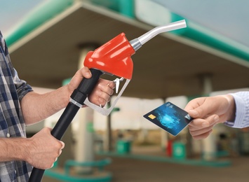 Image of Woman holding credit card and worker with fuel nozzle at gas station, closeup. Cashless payment