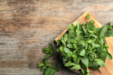 Board with fresh green mint on wooden table, top view. Space for text