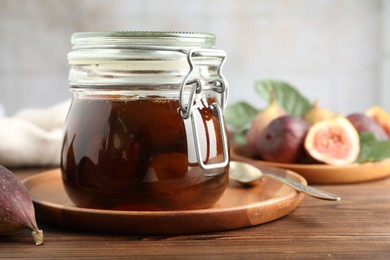 Photo of Jar of tasty sweet fig jam on wooden table