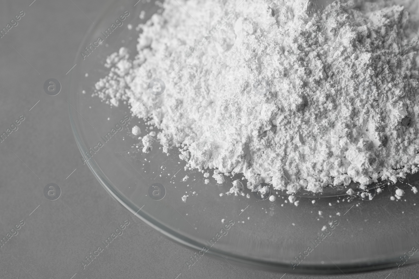 Photo of Plate with calcium carbonate powder on grey table, closeup