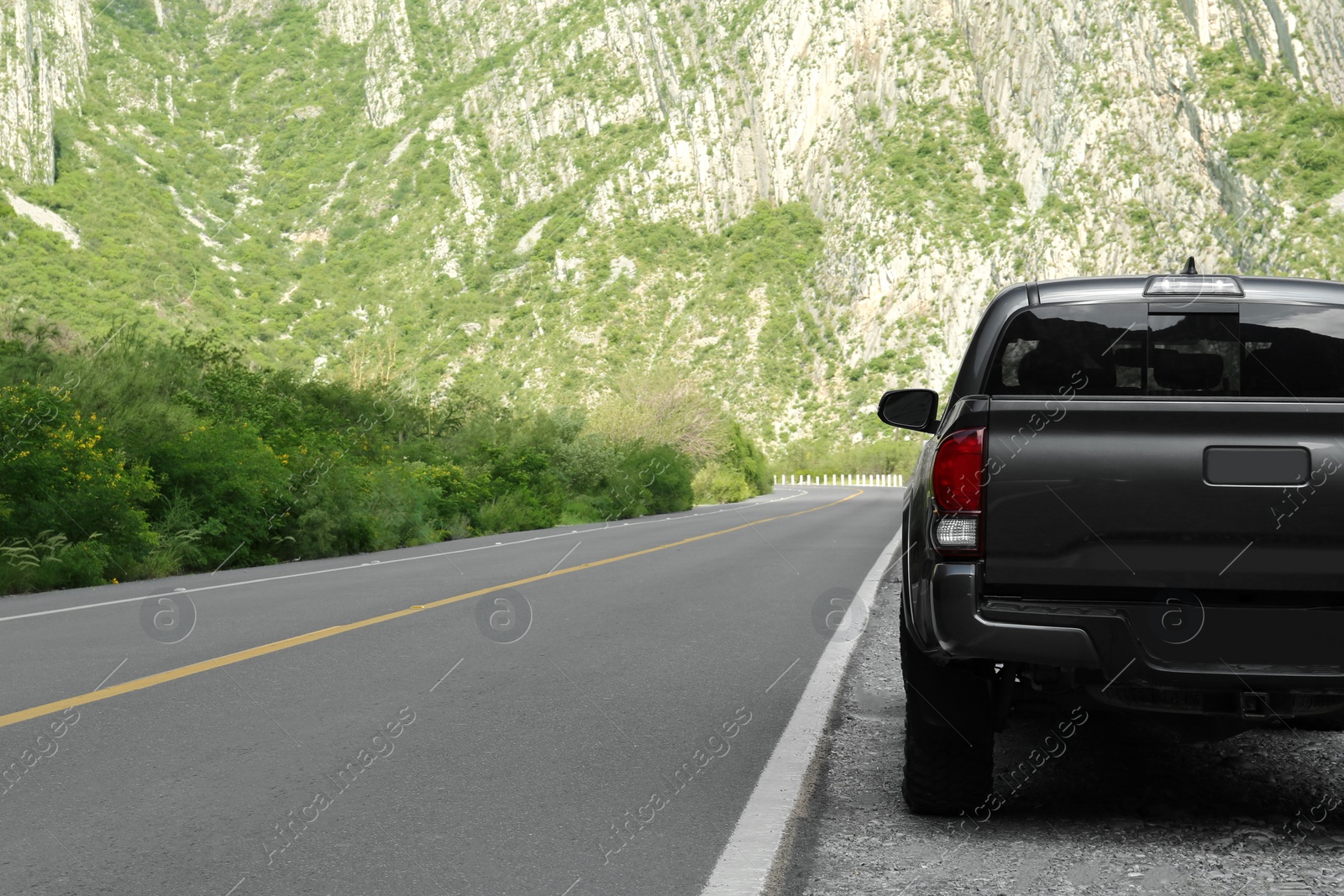 Photo of Picturesque view of big mountains, trees and road with black car