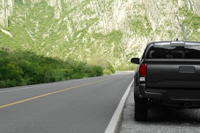 Photo of Picturesque view of big mountains, trees and road with black car