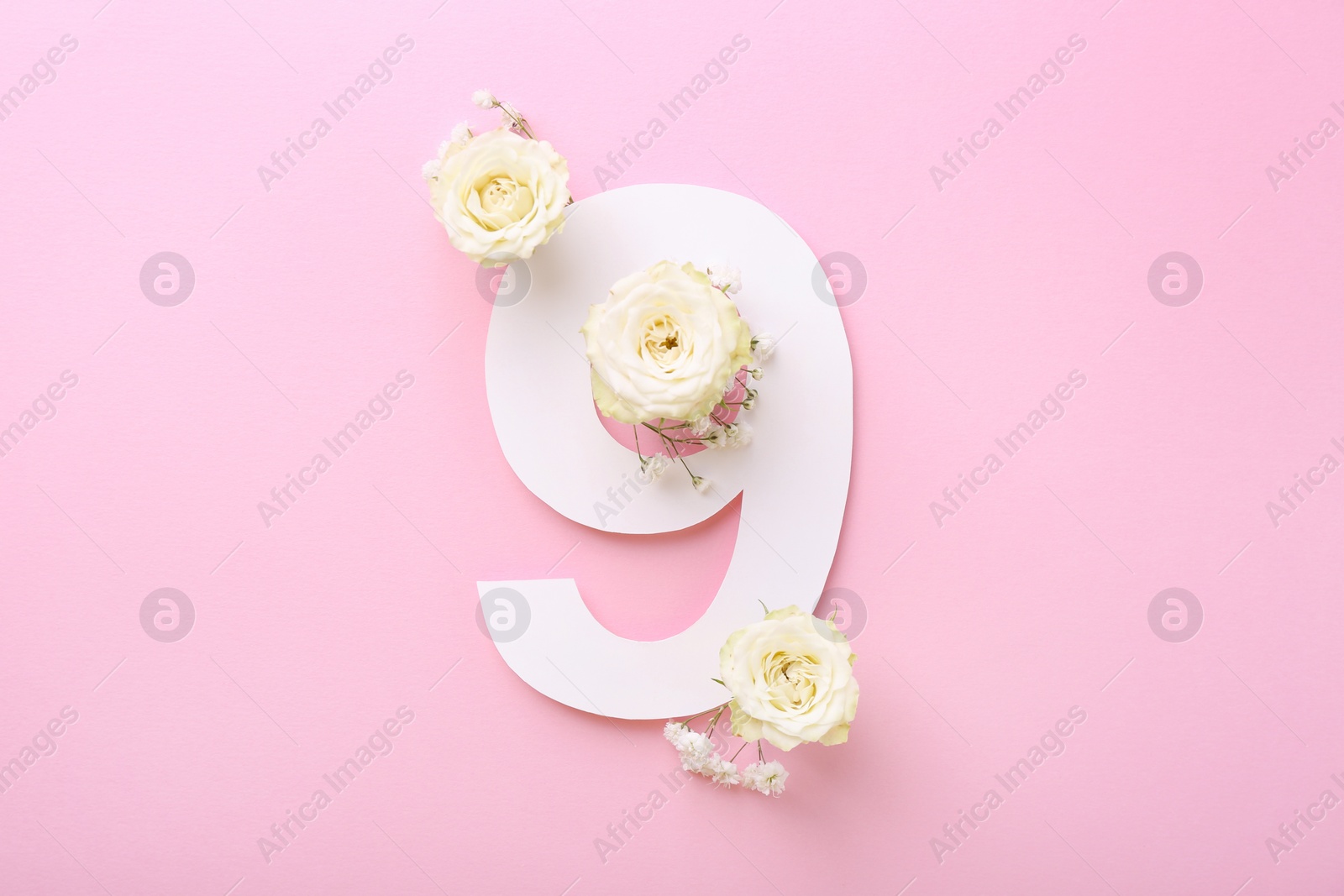 Photo of Paper number 9 and beautiful flowers on pink background, top view