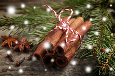 Different spices and fir tree branches on wooden table, closeup. Cinnamon, cloves, anise