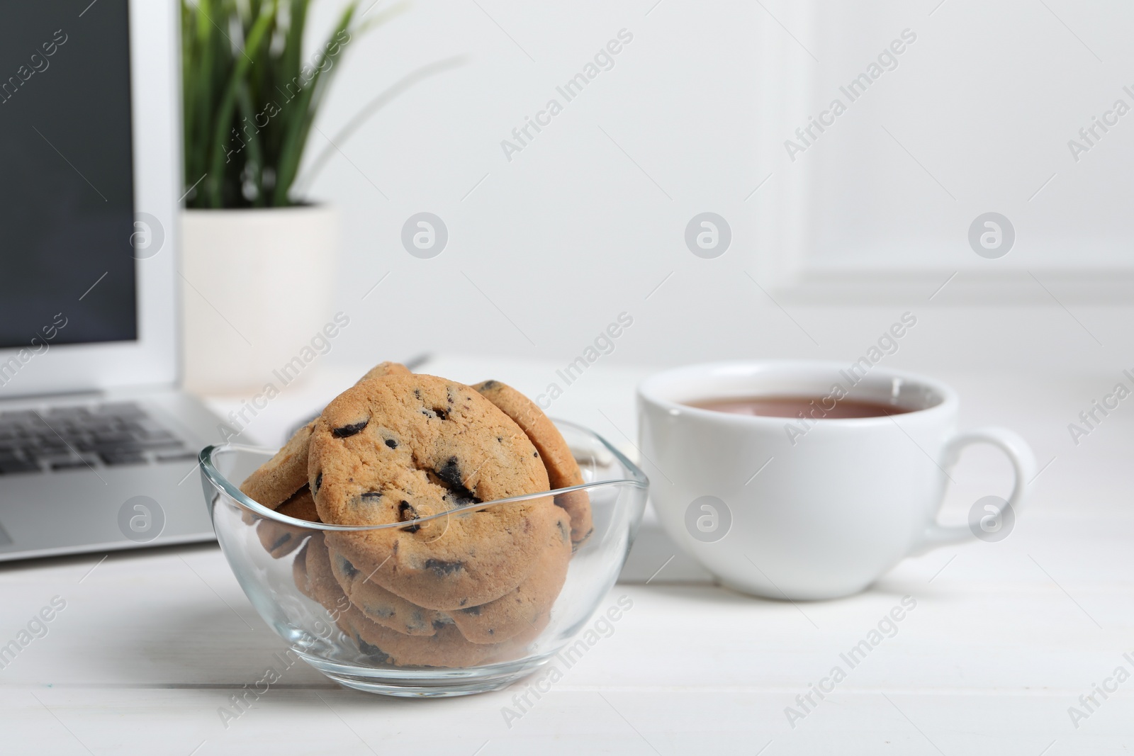 Photo of Chocolate chip cookies on white wooden table in office