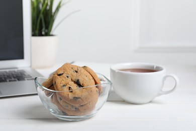 Photo of Chocolate chip cookies on white wooden table in office