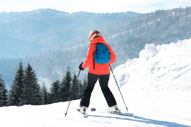 Woman skiing on snowy hill in mountains. Winter vacation