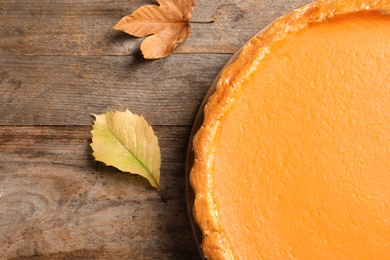 Fresh delicious homemade pumpkin pie on wooden background, top view. Space for text