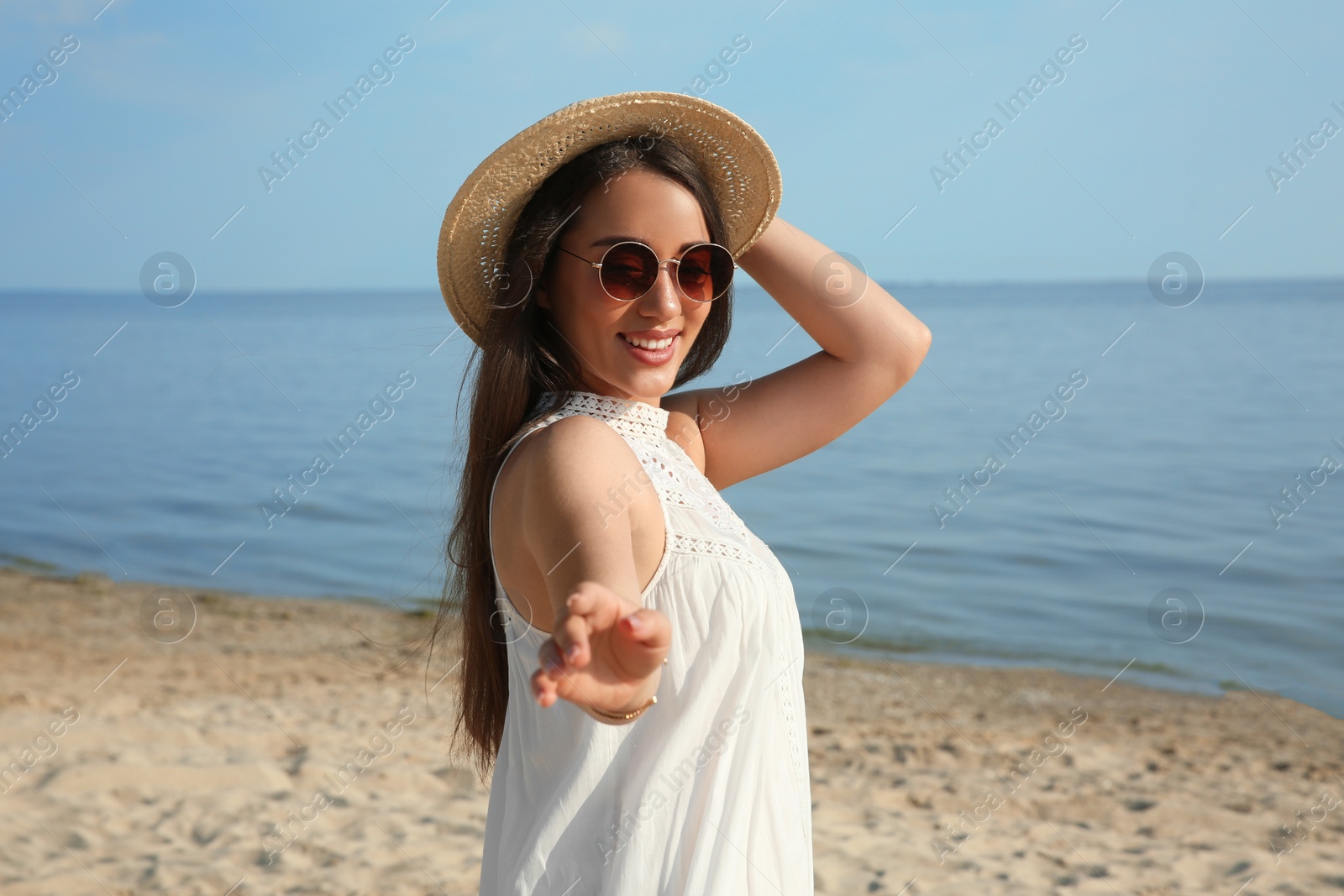 Photo of Beautiful young woman with straw hat and sunglasses on beach. Stylish headdress
